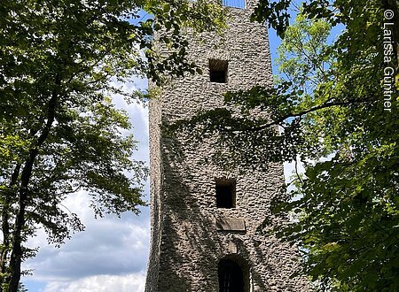 Wallerwarte (Ebermannstadt, Fränkische Schweiz) Steinerner Turm im Wald mit Bank im Vordergrund, blauer Himmel im Hintergrund.